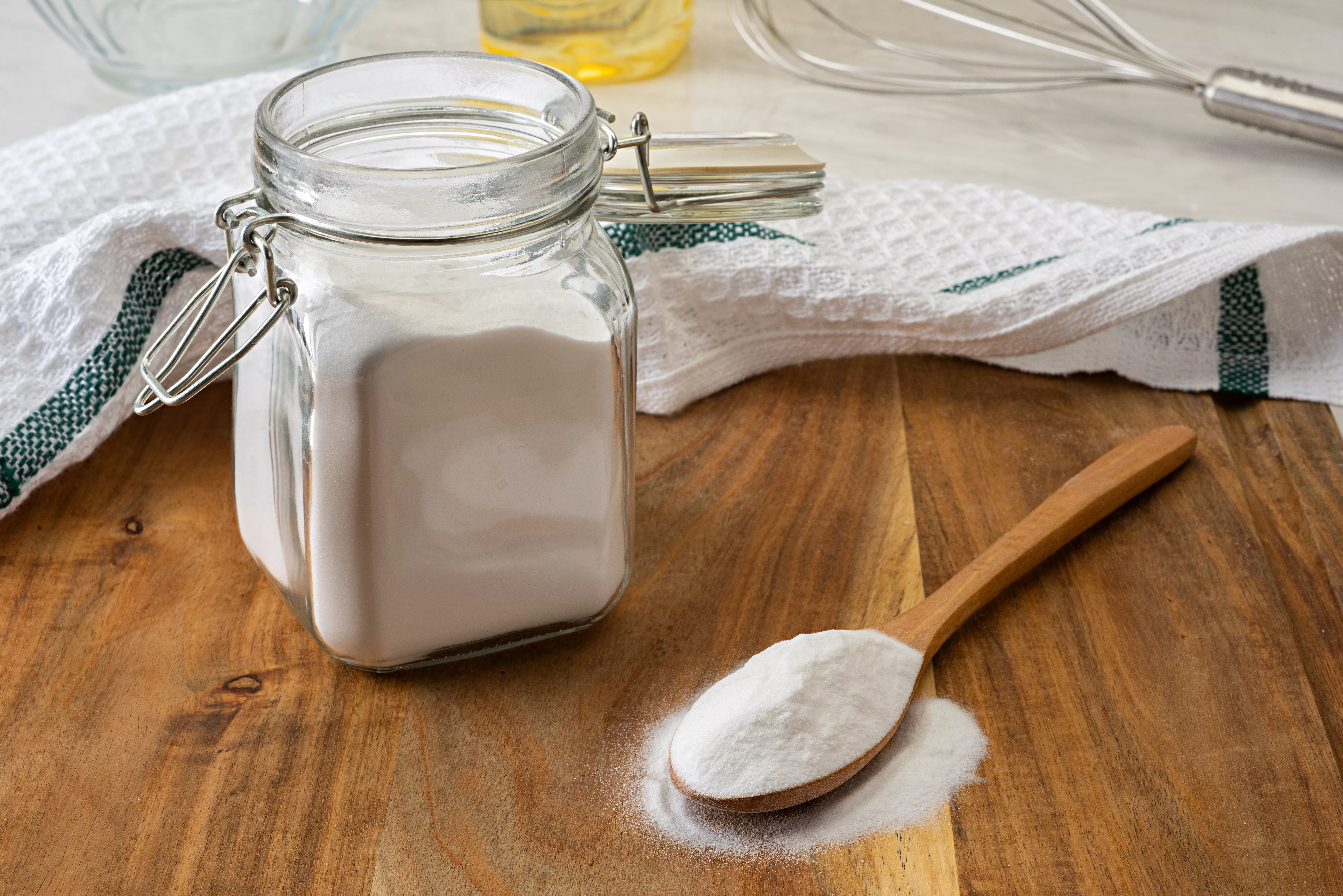 jar of baking soda with wooden spoon on wood countertop